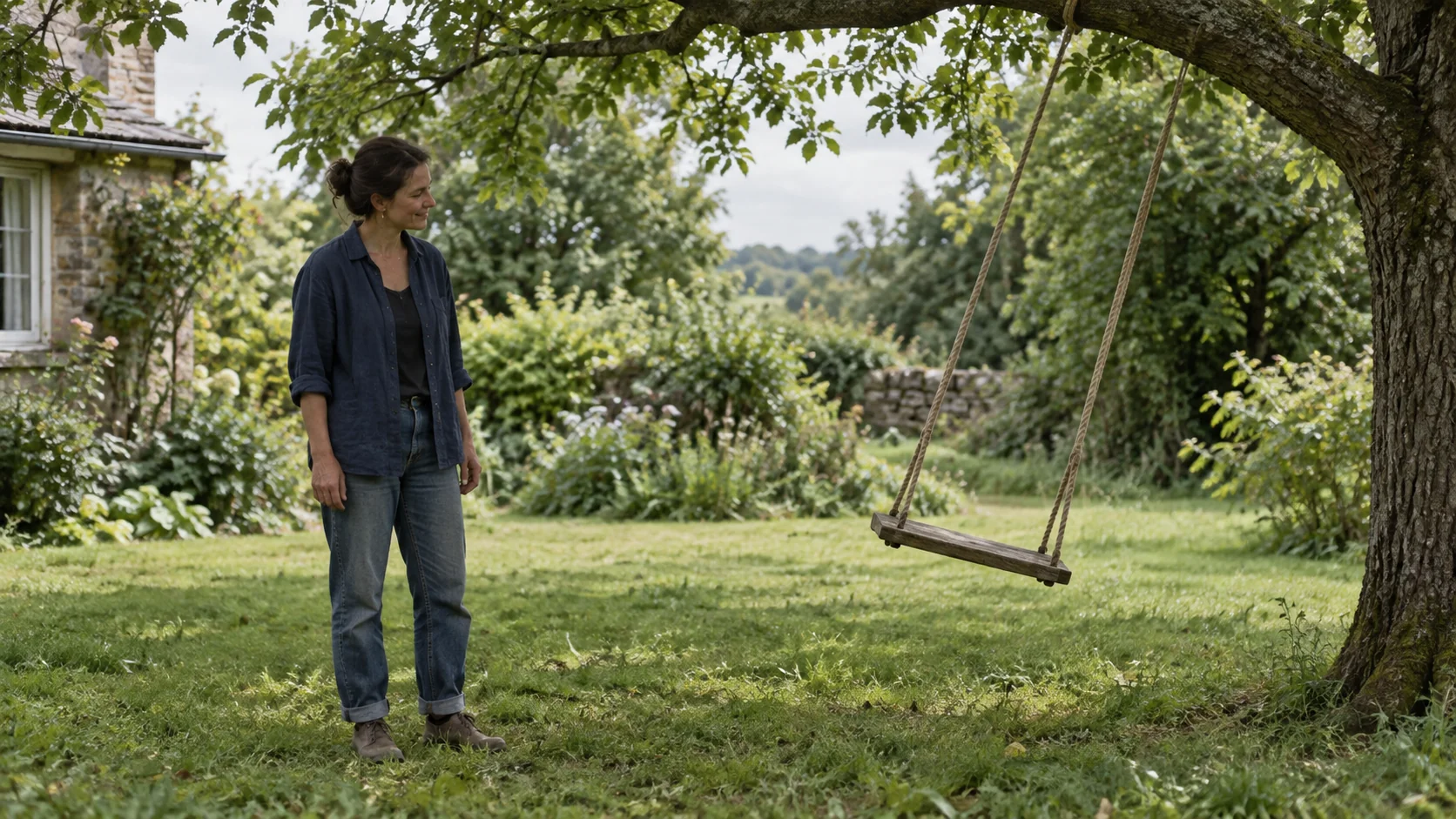 A woman watches an empty wooden tree swing suspended to one side of its arc