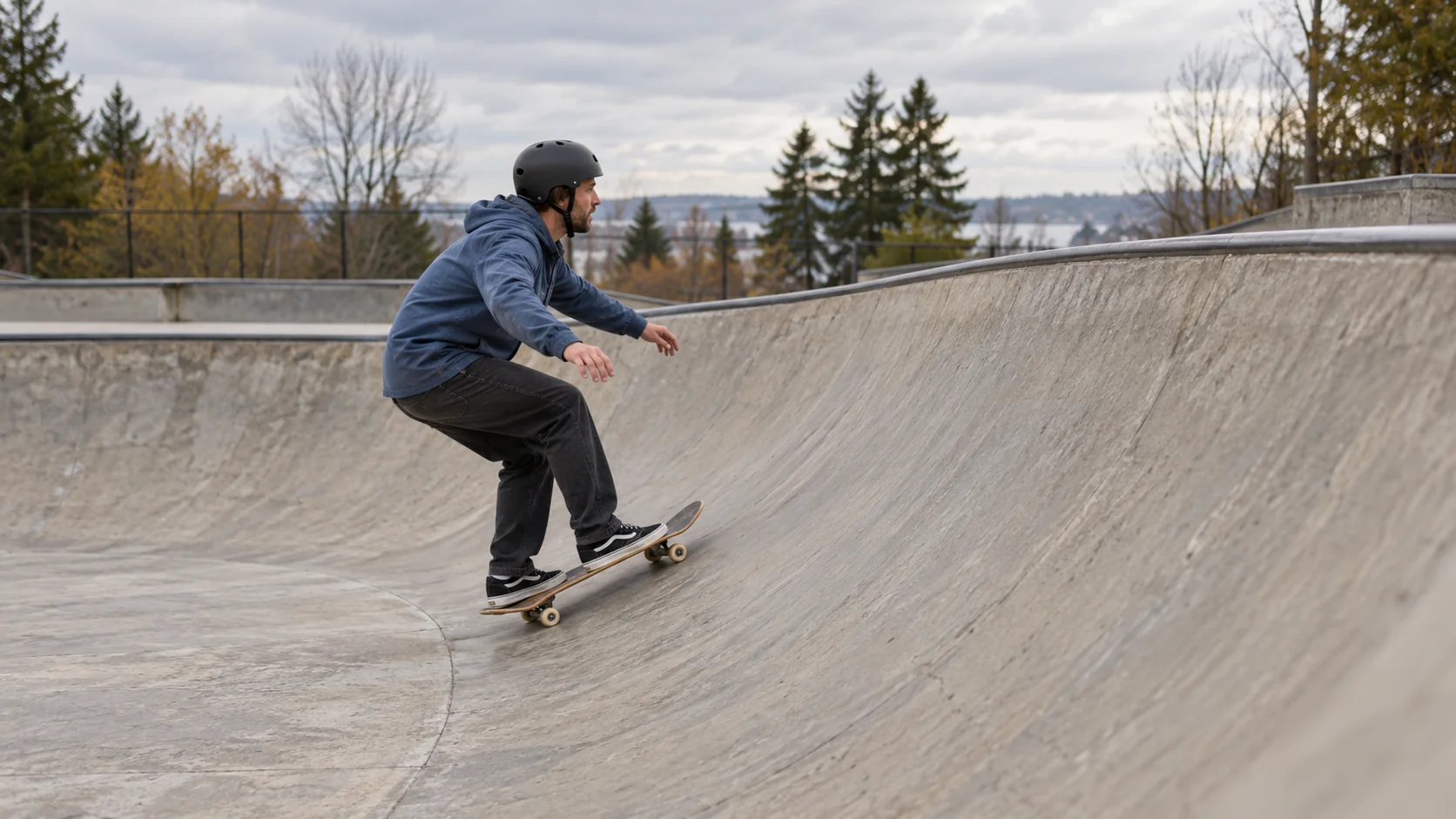An adult skateboarder coasts up a concrete bowl below its higher rim